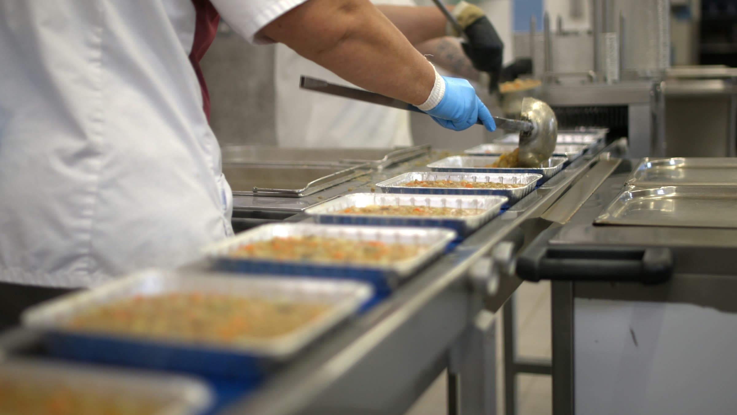 Barquettes de plats cuisinés garnies sur un convoyeur